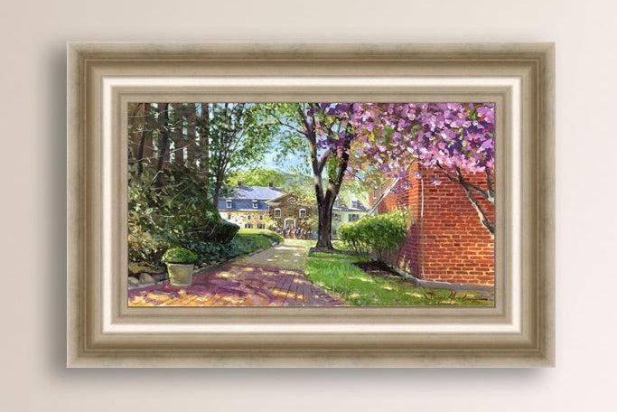 A canvas print depicting a vibrant spring scene with a pathway, trees in bloom, and a historic Moravian Chapel in the background.