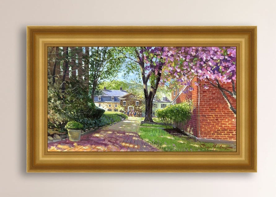 A canvas print depicting a vibrant spring scene with a pathway, trees in bloom, and a historic Moravian Chapel in the background.