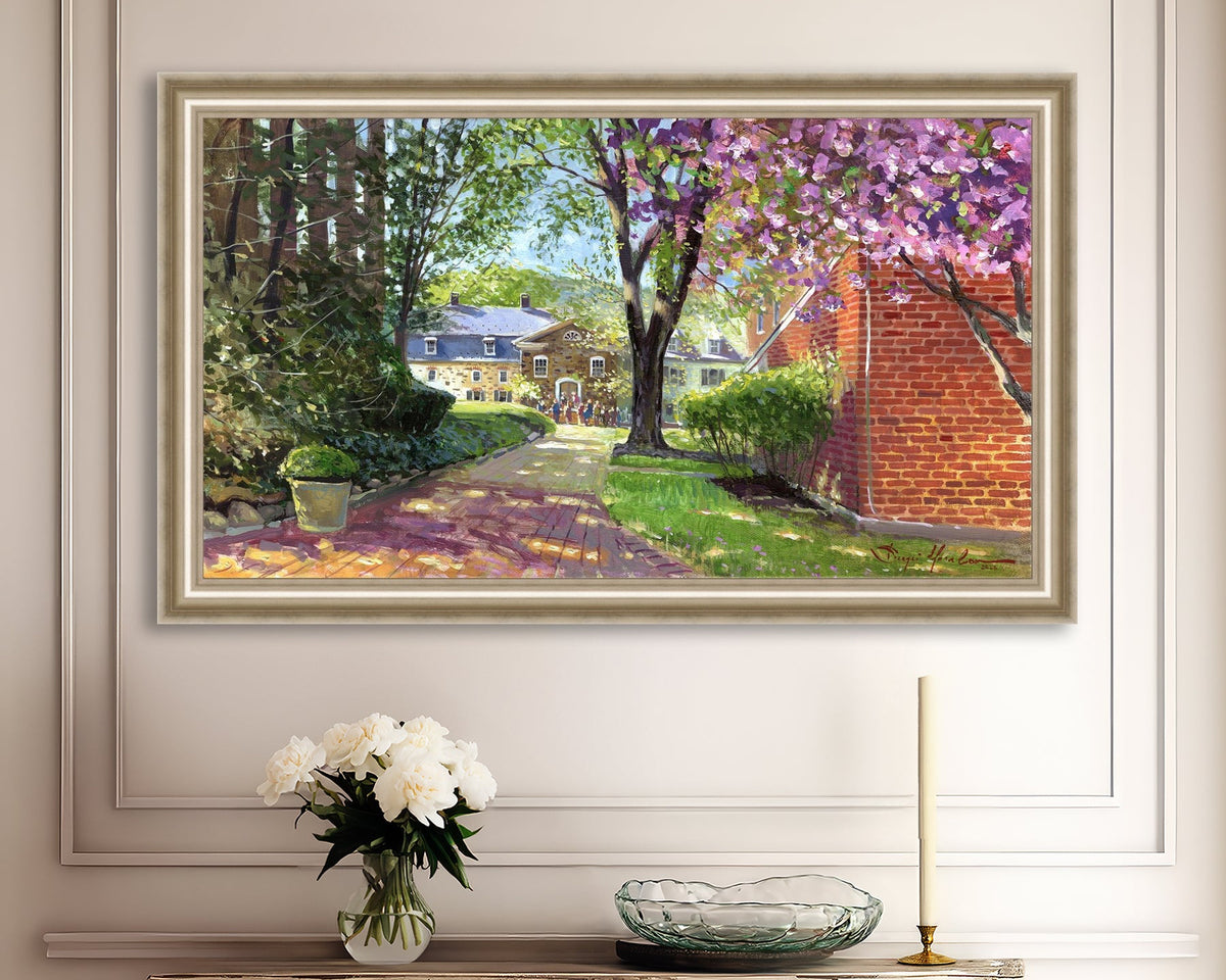 A canvas print depicting a vibrant spring scene with a pathway, trees in bloom, and a historic Moravian Chapel in the background.