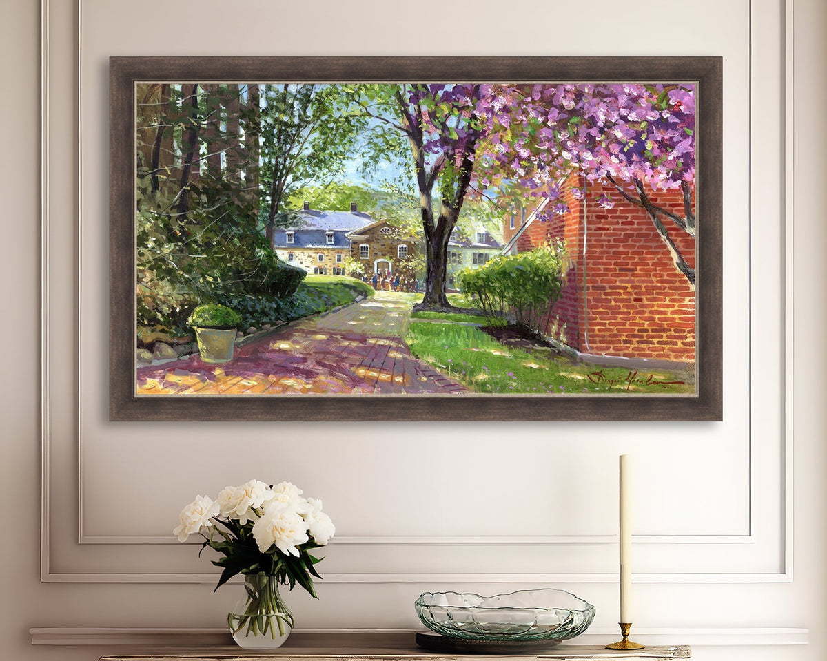 A canvas print depicting a vibrant spring scene with a pathway, trees in bloom, and a historic Moravian Chapel in the background.