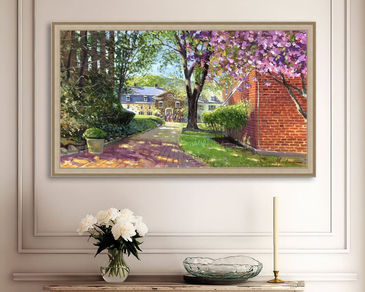 A canvas print depicting a vibrant spring scene with a pathway, trees in bloom, and a historic Moravian Chapel in the background.