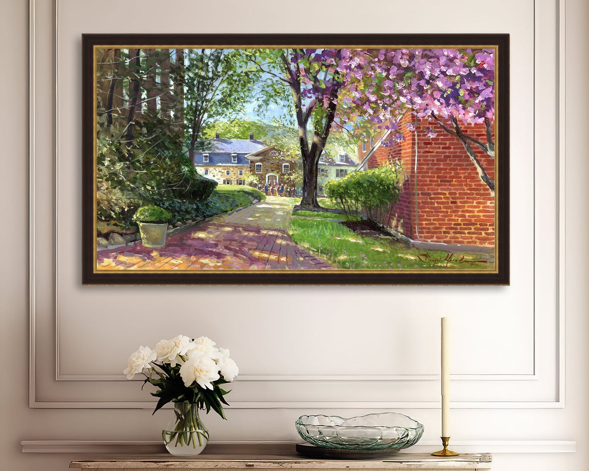 A canvas print depicting a vibrant spring scene with a pathway, trees in bloom, and a historic Moravian Chapel in the background.