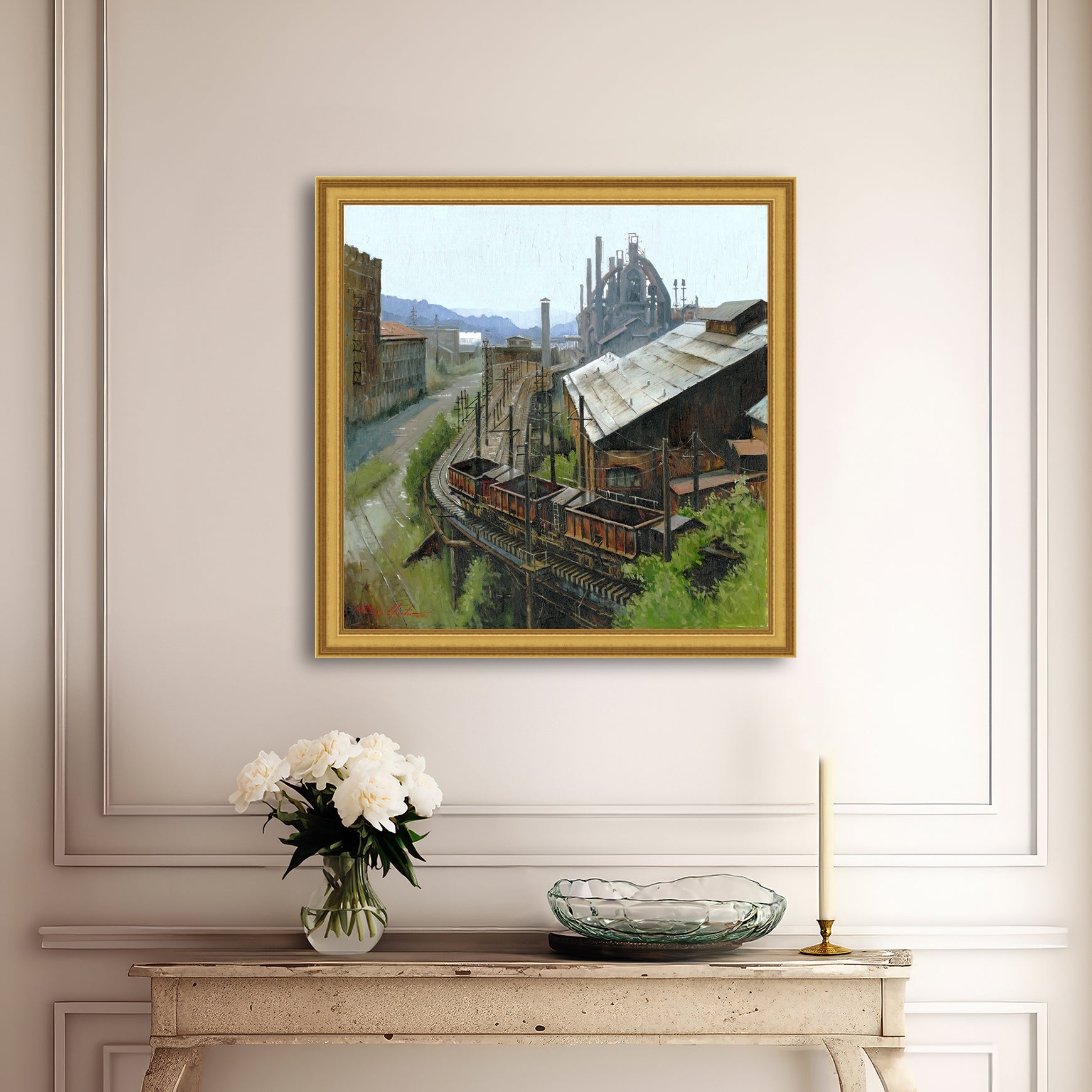 Framed painting of an industrial scene on a wall above a console table with decor items.