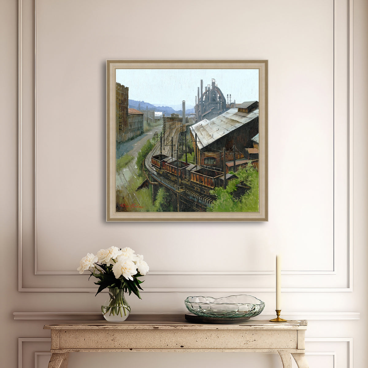 Framed industrial scene painting on a wall above a console table with decor items.