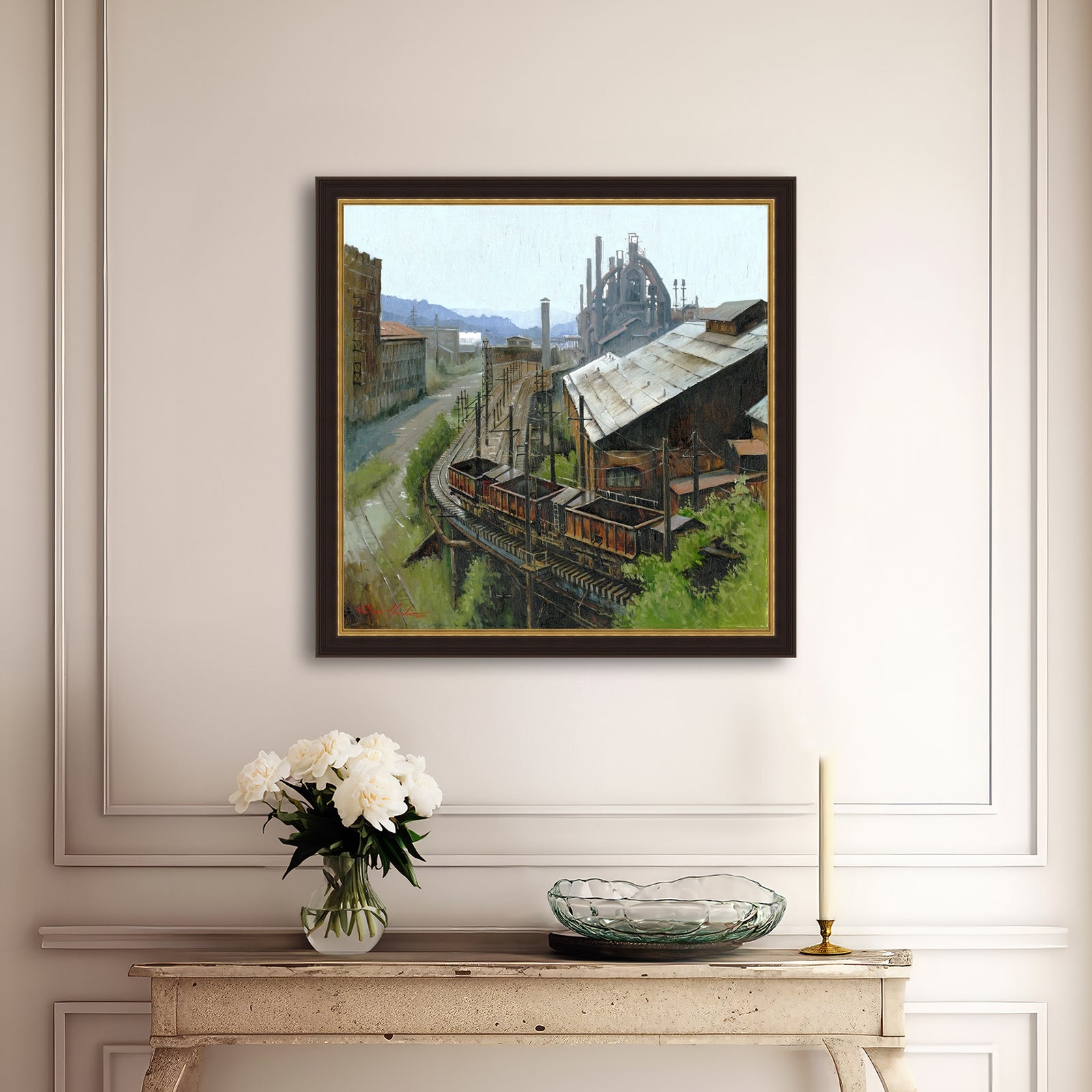 Framed painting of an industrial scene on a wall above a console table with decor items.