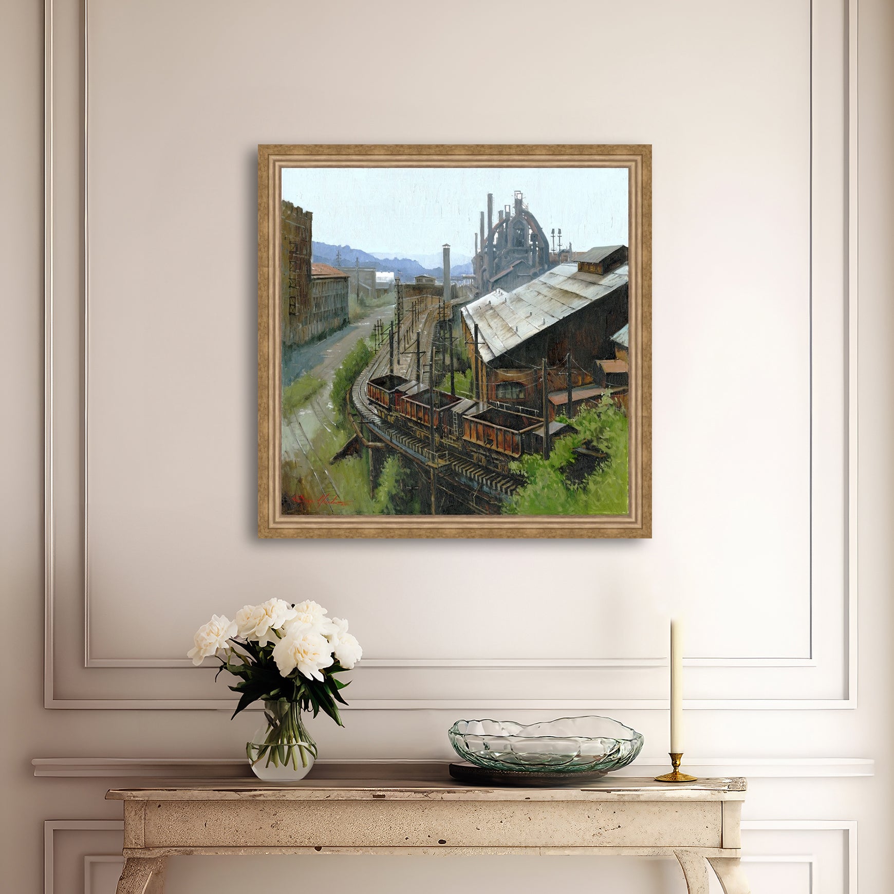 Framed painting of an industrial scene on a wall above a console table with decor items.