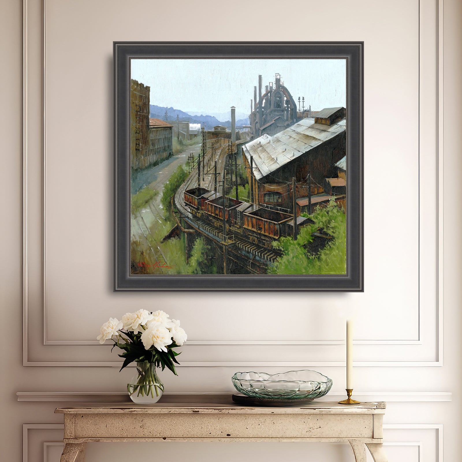 Framed painting of an industrial scene on a wall above a console table with decorative items.