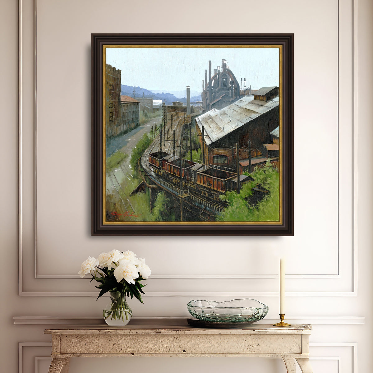 Framed painting of an industrial scene on a wall above a console table with decorative items.