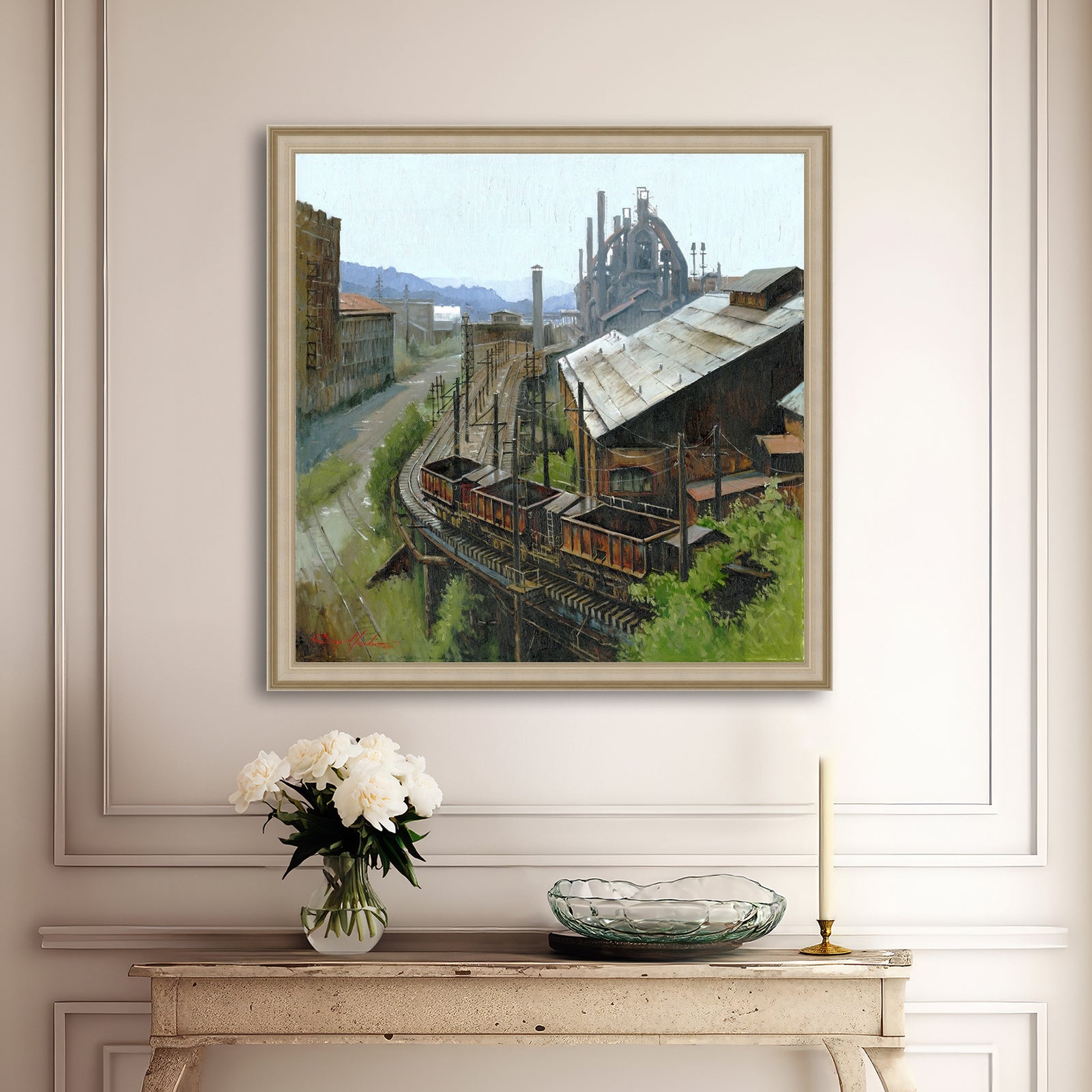 Framed painting of an industrial scene above a console table with decorative items.