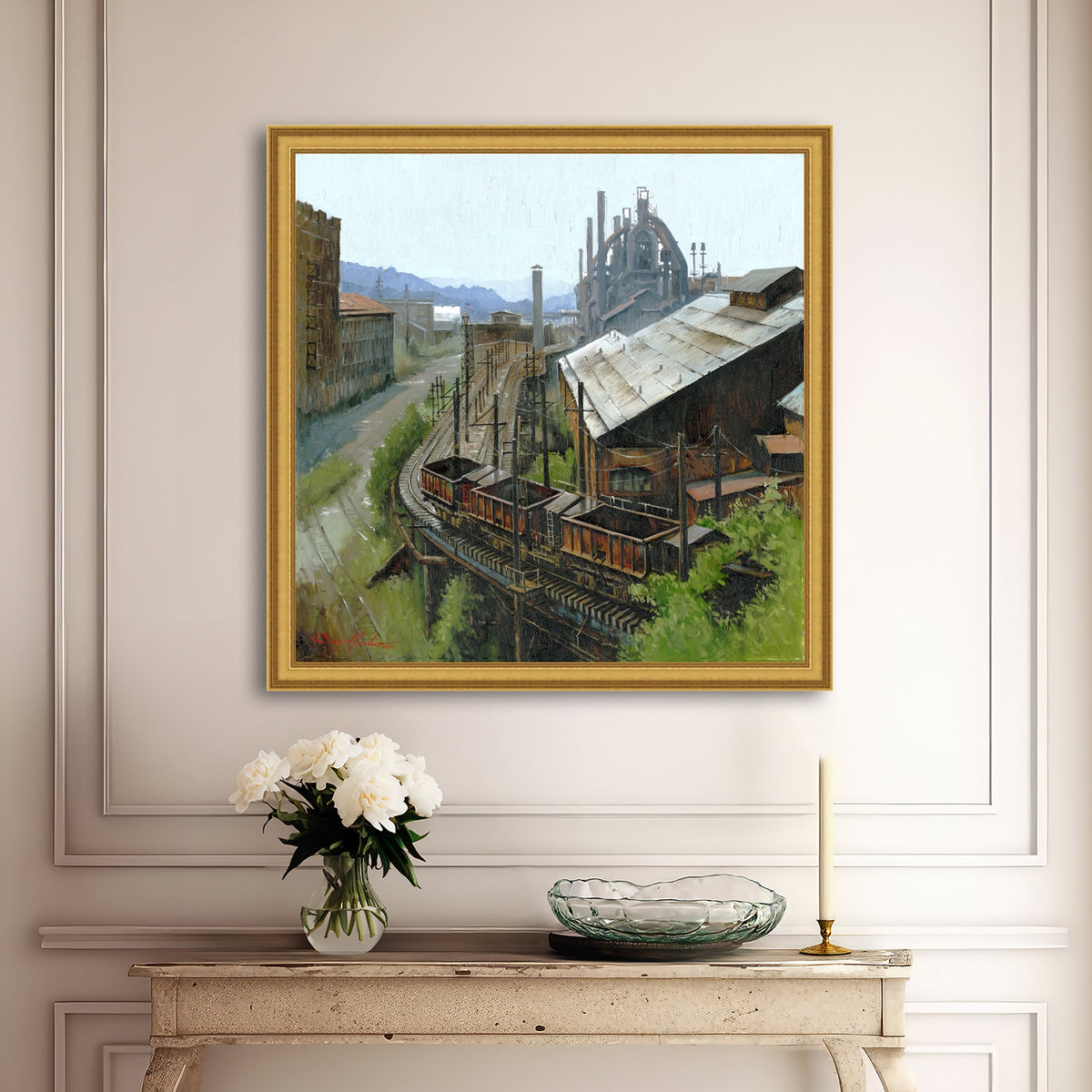Framed painting of an industrial scene above a console table with decorative items.