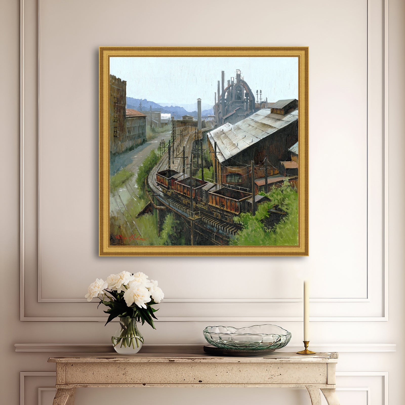 Framed painting of an industrial scene above a console table with decorative items.