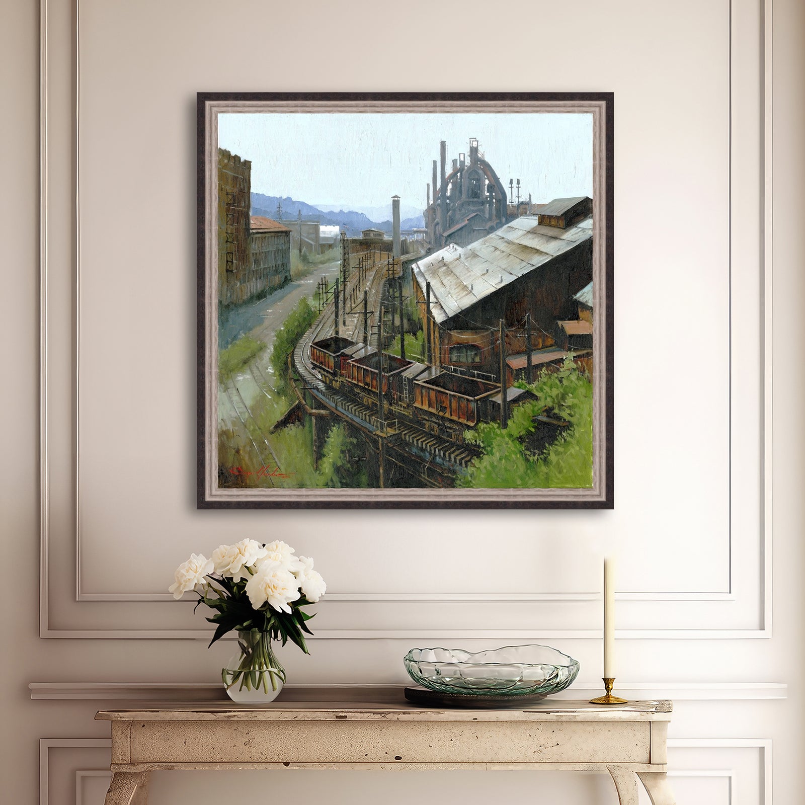 Framed industrial scene painting on a wall above a console table with decorative items.