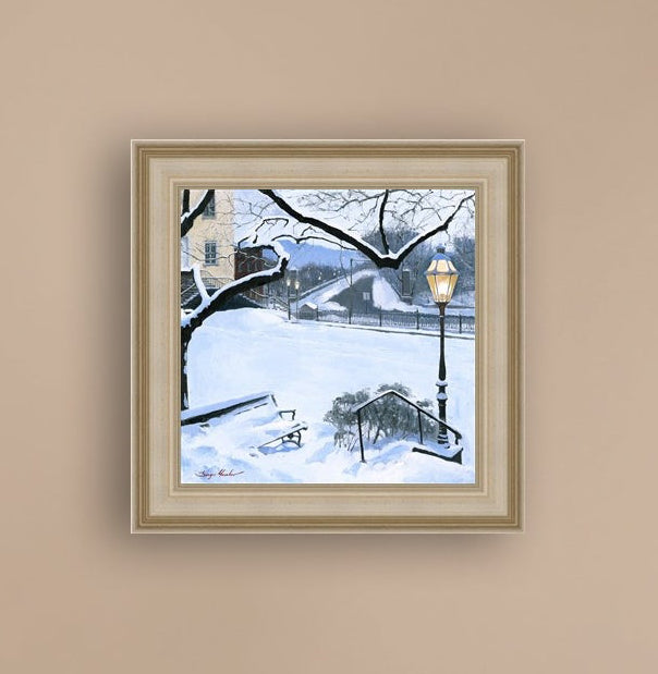 A canvas print featuring a snowy landscape with a bench, a lamp post, in the foreground, and Moravian Church in the background.
