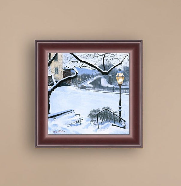A canvas print featuring a snowy landscape with a bench, a lamp post, in the foreground, and Moravian Church in the background.