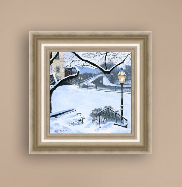 A canvas print featuring a snowy landscape with a bench, a lamp post, in the foreground, and Moravian Church in the background.