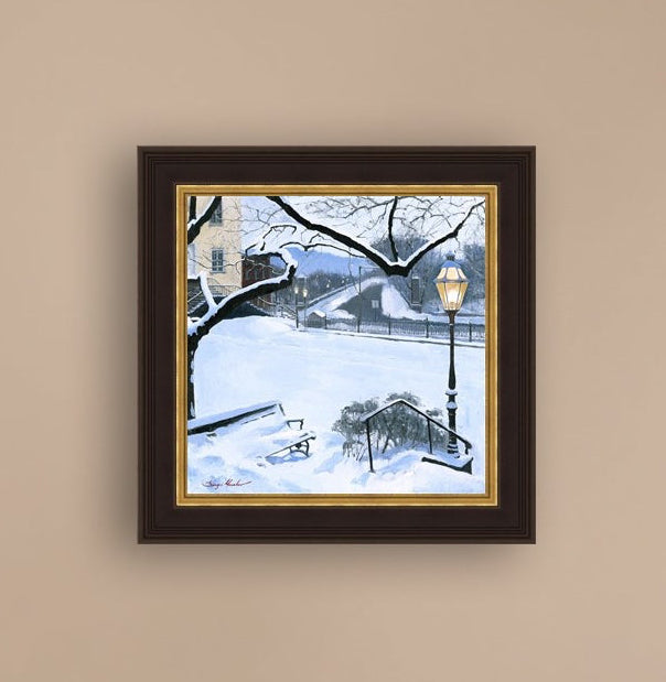 A canvas print featuring a snowy landscape with a bench, a lamp post, in the foreground, and Moravian Church in the background.
