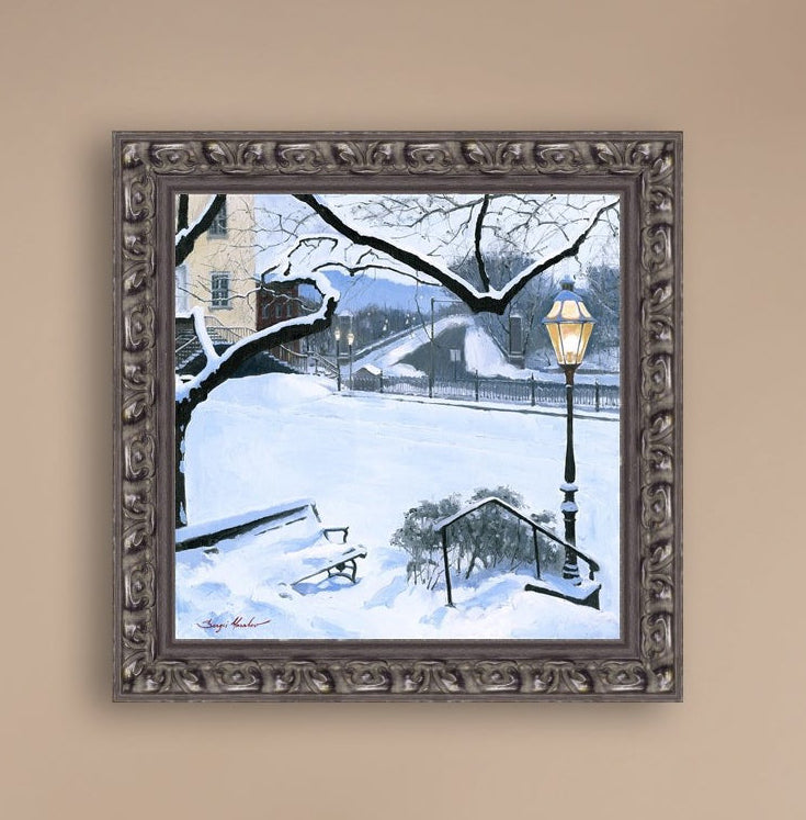A canvas print featuring a snowy landscape with a bench, a lamp post, in the foreground, and Moravian Church in the background.